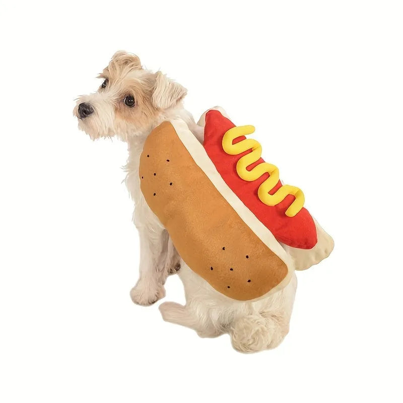 A small dog wearing a red and brown plush hot dog costume with a hood and leg openings.