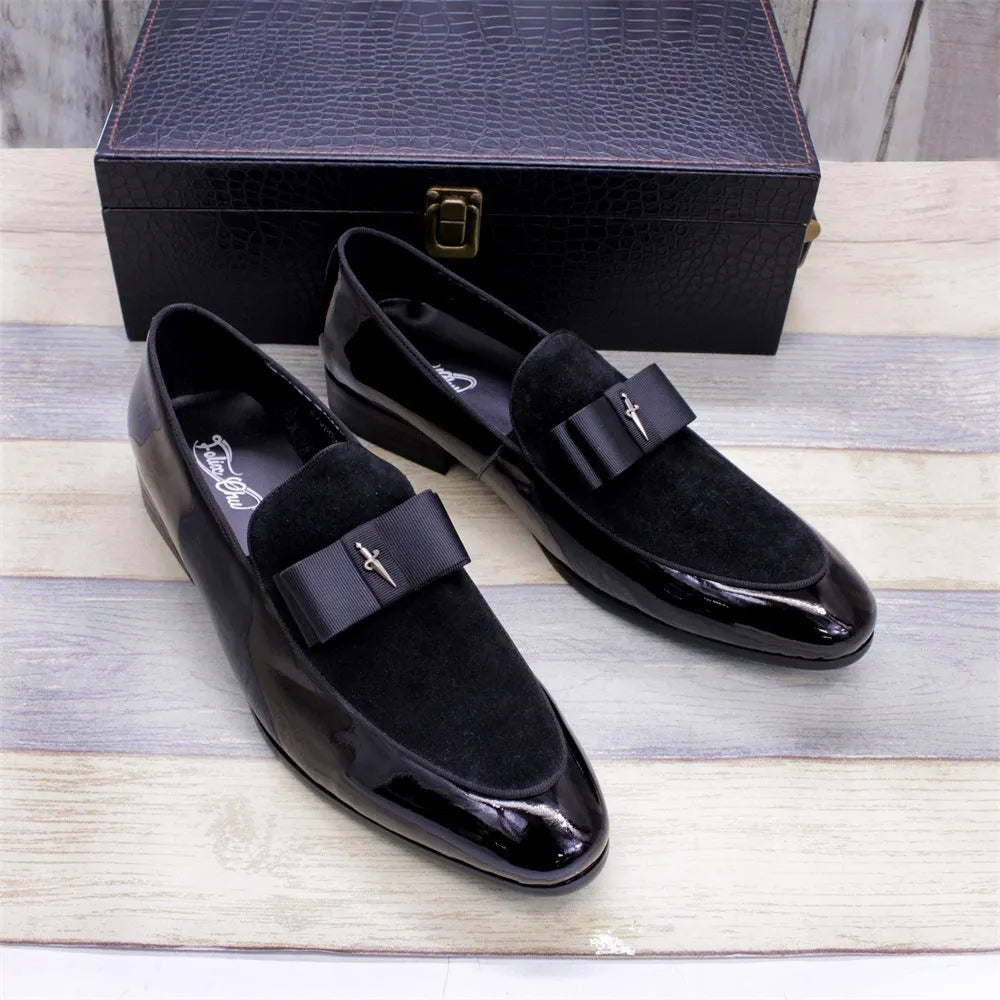 Men's black and brown tassel loafers with a matte and patent leather upper on a wooden floor.