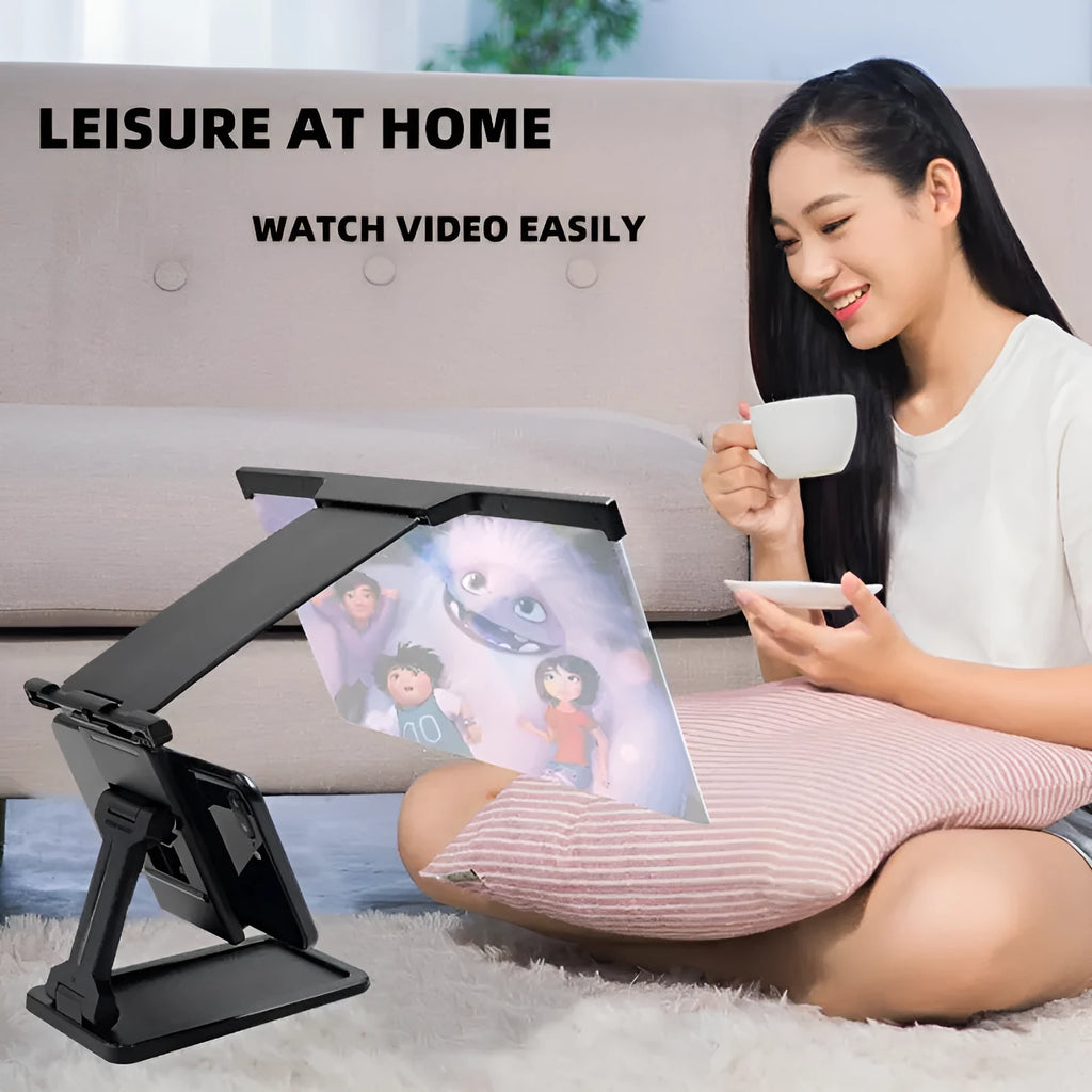 Black folding mobile phone screen magnifier and detachable phone holder on a desk.