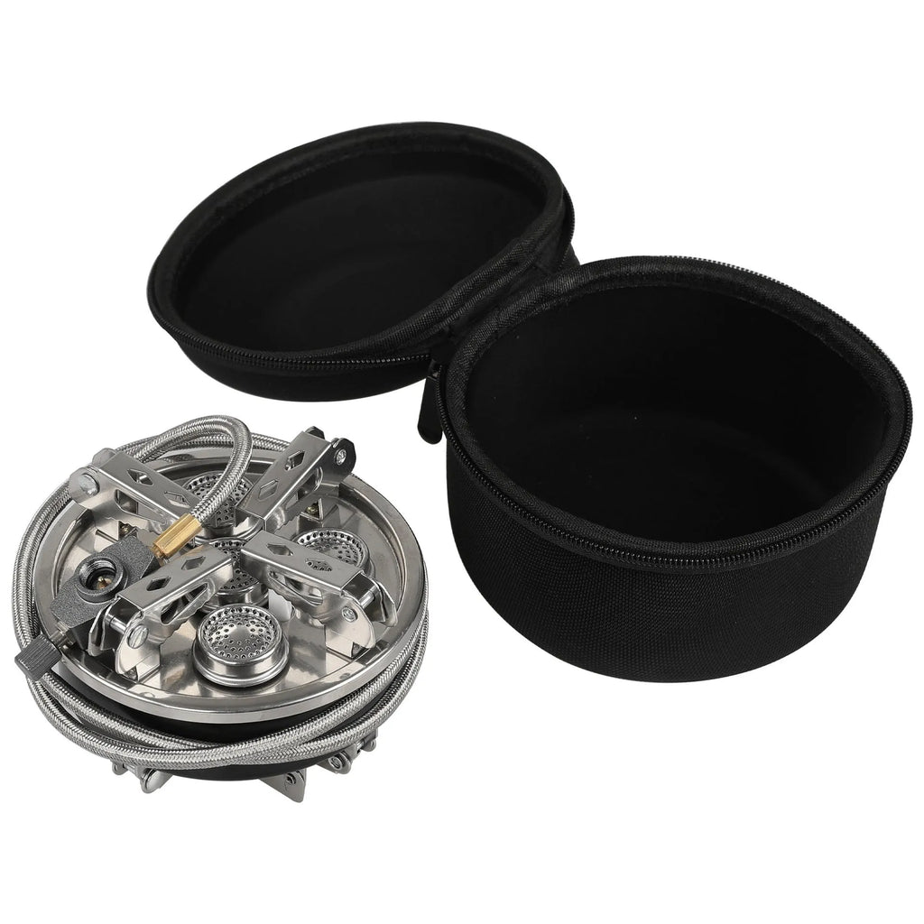 Silver portable folding camping stove with extended copper gas hose, shown on a wooden picnic table.