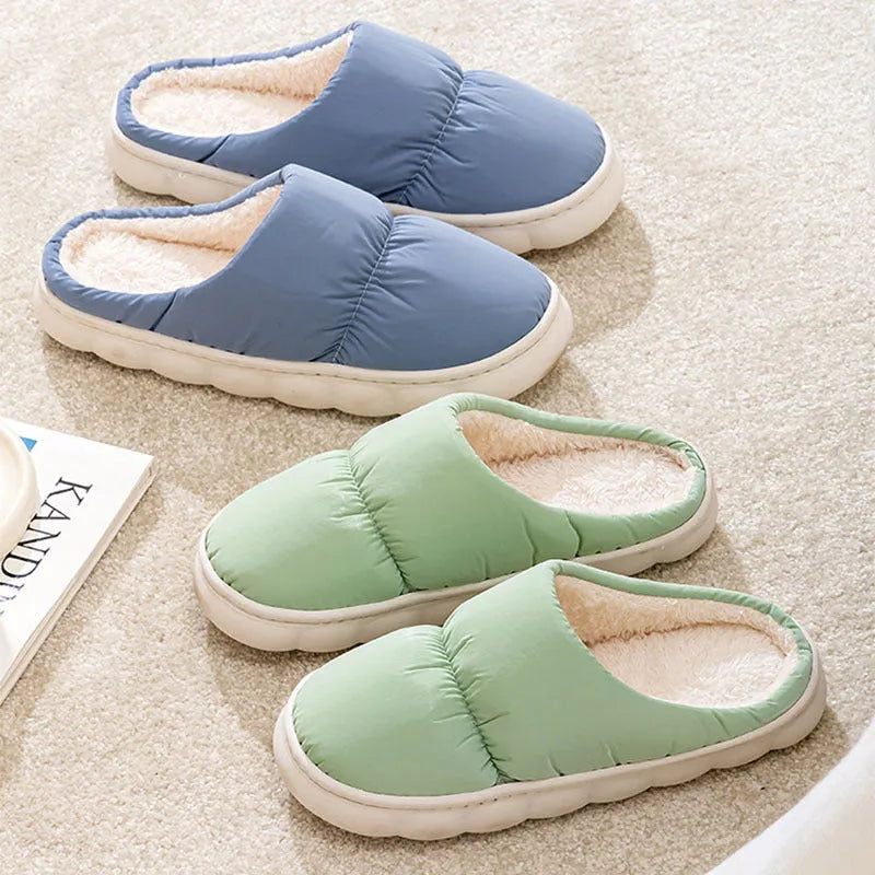 Blue down cotton winter slippers with a thick rubber sole and plush lining, shown on a wooden floor.