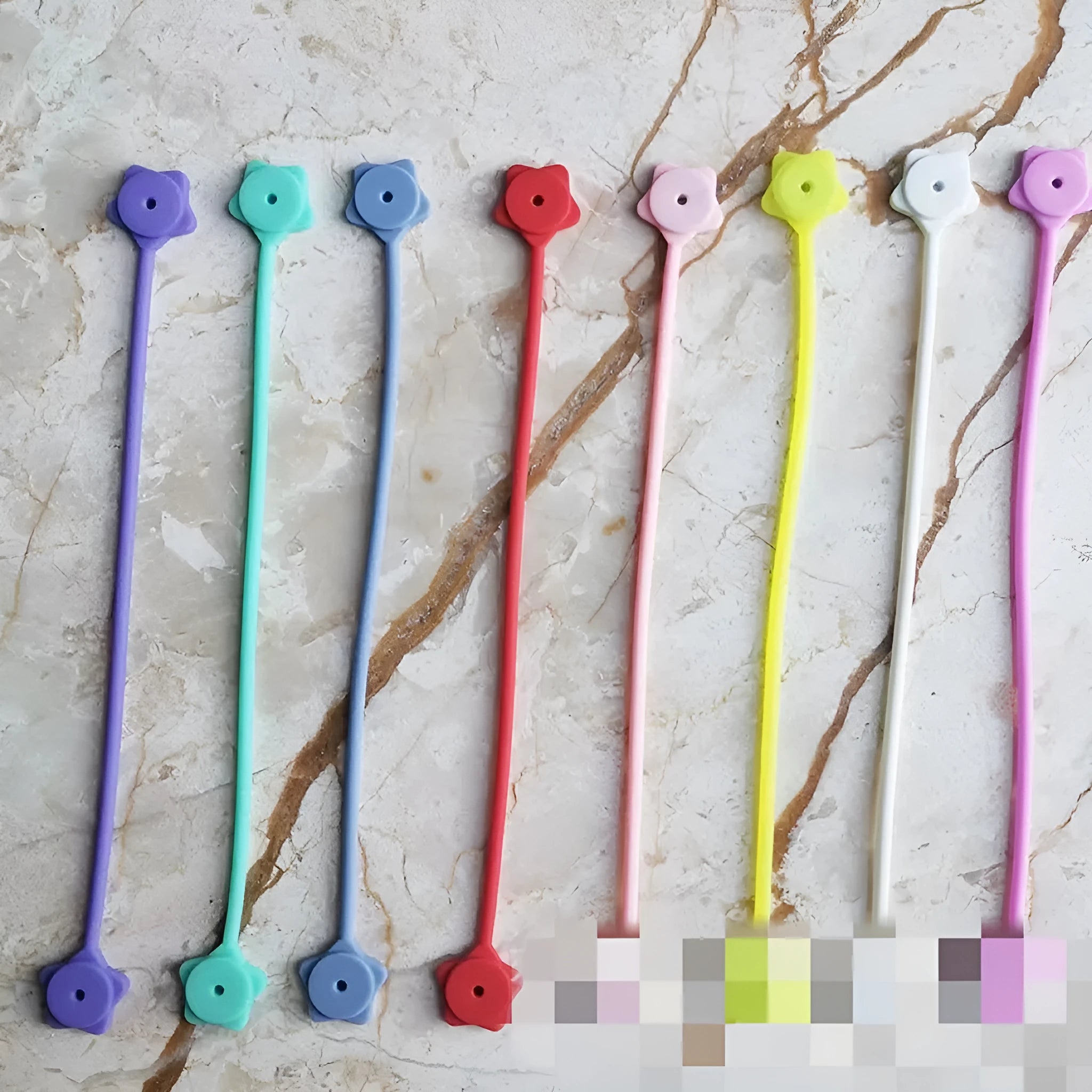 Purple silicone wire winder with magnet for organising headphone cables on a metal surface.