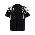 Black loose fit short-sleeved T-shirt with padded shoulders featuring rivet and ribbon detail.