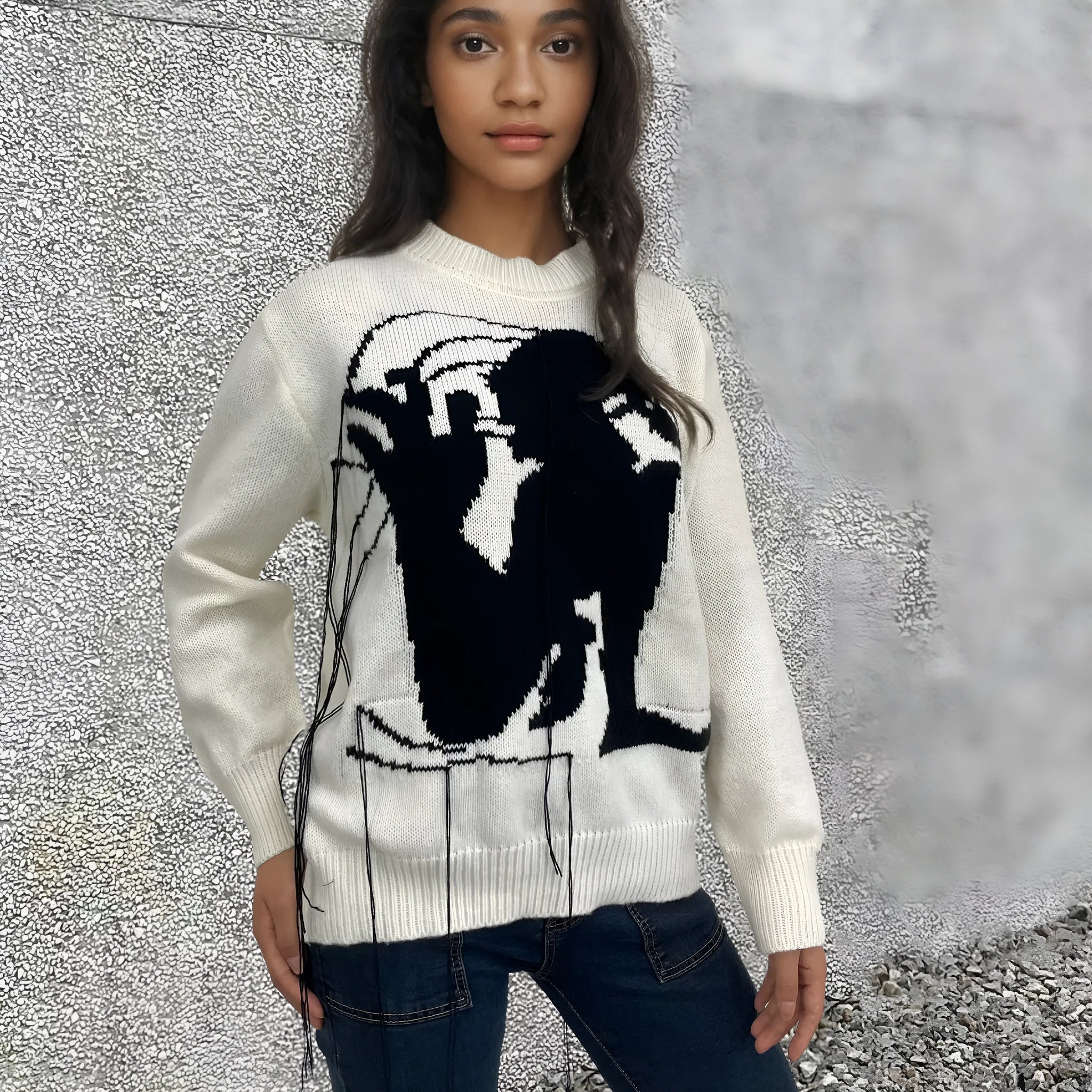 Grey women's alpaca wool sweater with abstract pattern and tassel detailing on a hanger.