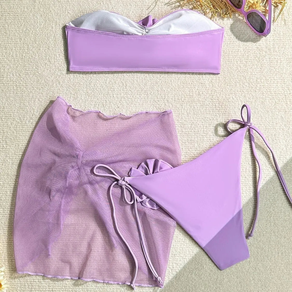 Women's pink swimsuit set with floral tie tube top, matching bottoms, and detachable skirt laid flat.