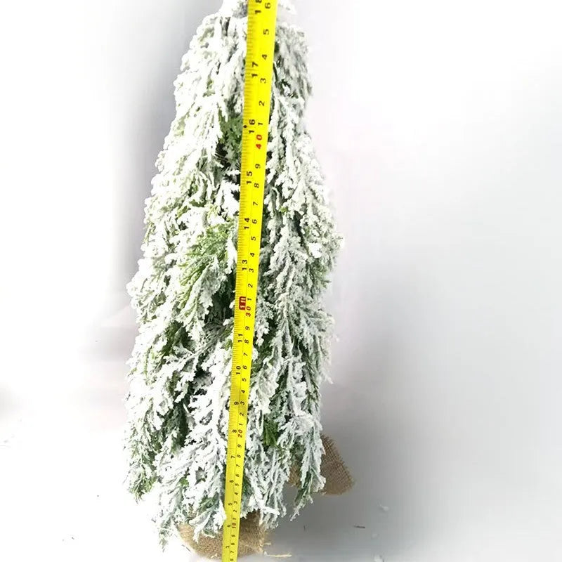 Small 24-inch plastic Christmas tree with LED lights and snow-covered branches on desktop