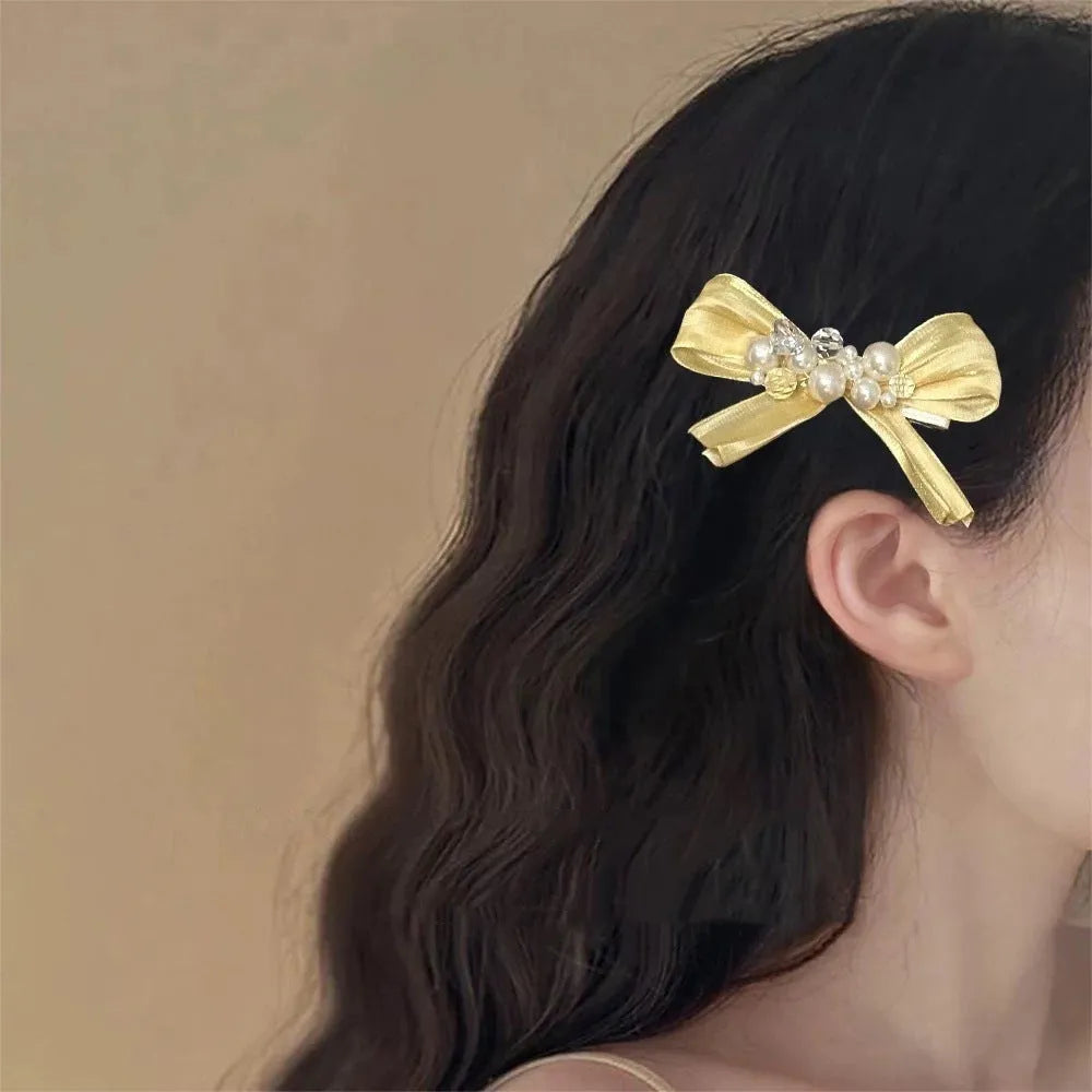 Yellow cloth bow hair clip with rhinestone pearls on duckbill clip mechanism