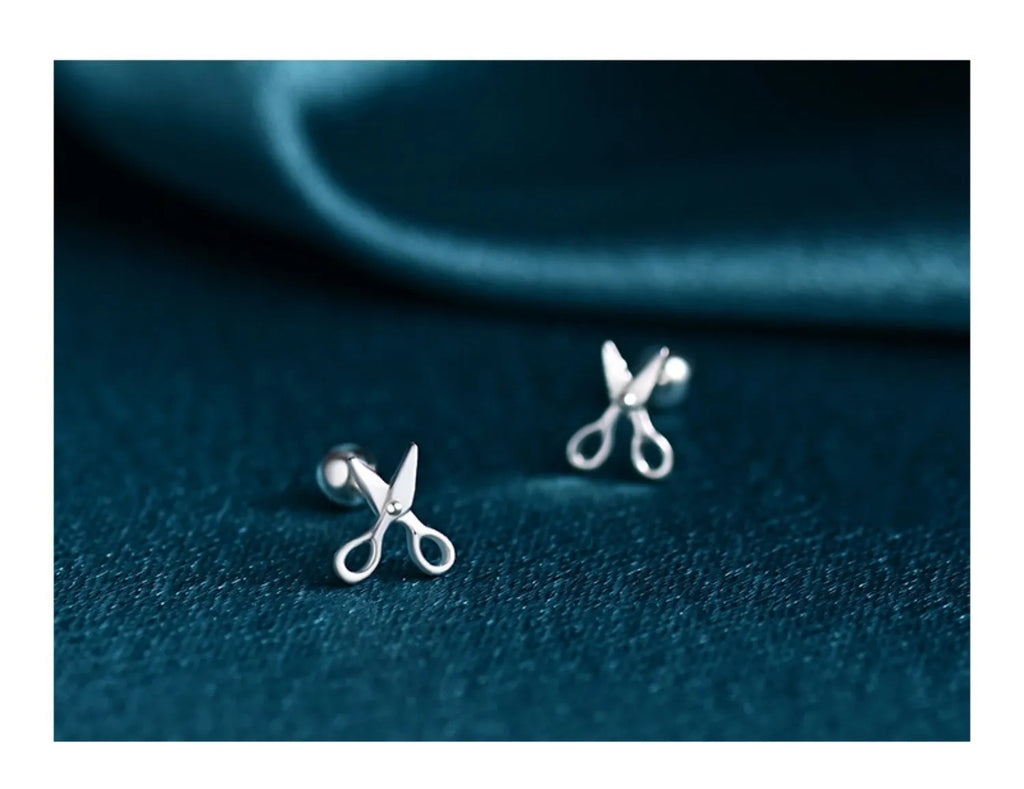 A pair of screw-back earrings made from 999 pure silver with a miniature silver scissors charm.