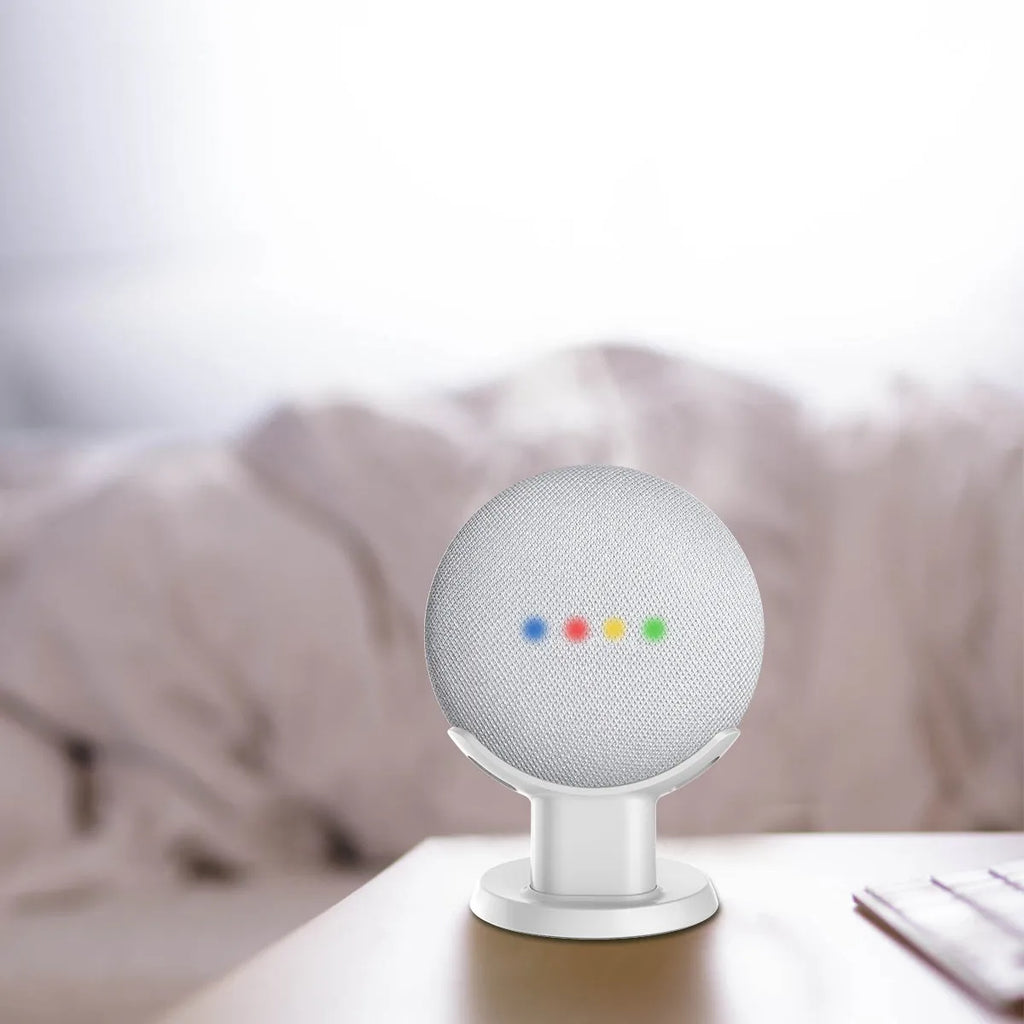 Black plastic stand holding Google Home Mini speaker on wooden desk