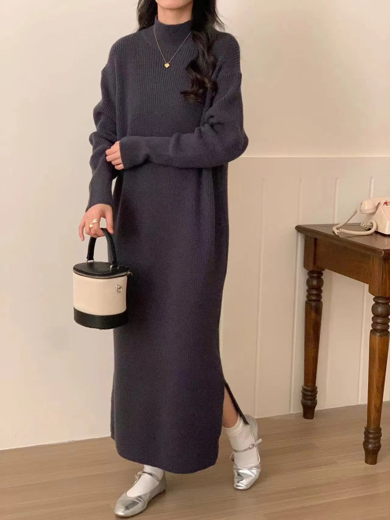 Woman wearing a milky white half turtleneck long sleeve knitted midi dress with a high waist.