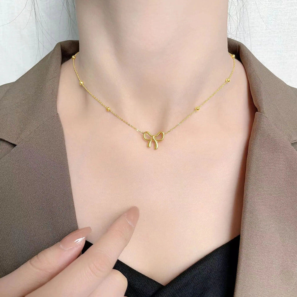 Gold bow necklace on adjustable cross chain for women