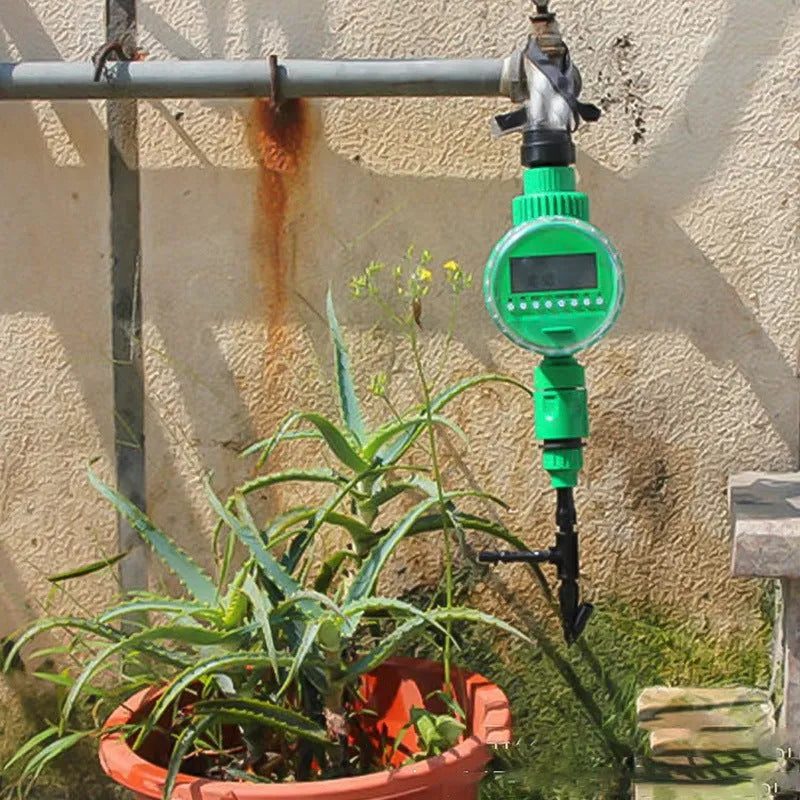 Green plastic automatic watering timer with digital display for garden hose connection.