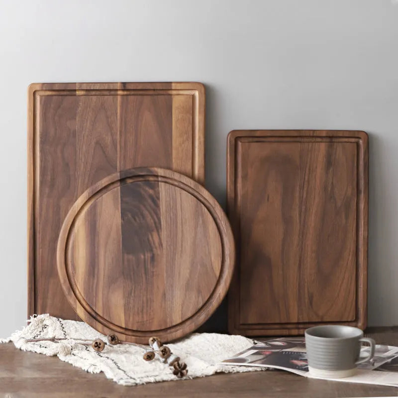 Black walnut wood cutting board set showing rectangular and round boards with juice grooves and side handles