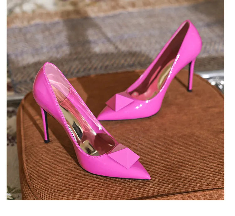 Pink patent leather women's stiletto heels with an ankle buckle and pointed toe.