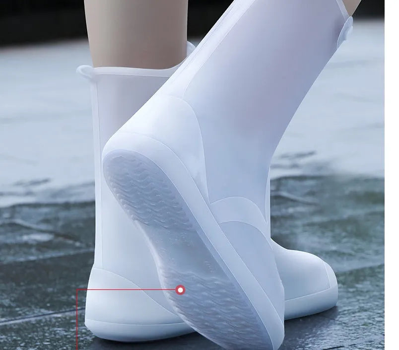 White high-top reusable PVC waterproof shoe covers with anti-skid sole on a wet surface.