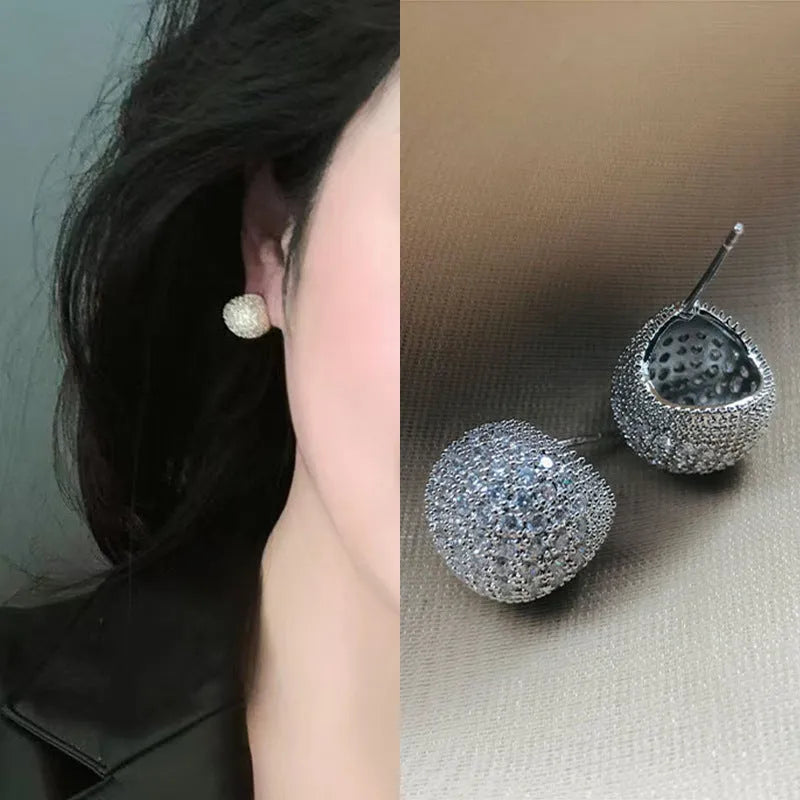 Geometric drop-shaped ear clips with spherical elements in gold and white colour options