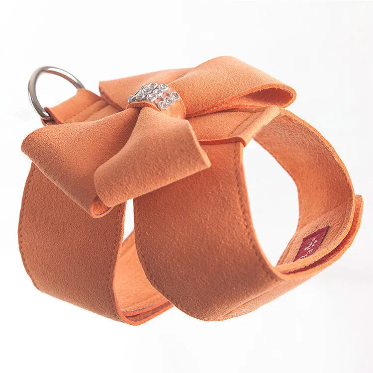 A pink microfiber dog chest strap with a white bowknot, showing the adjustable size buckles.
