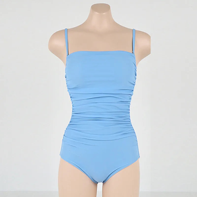Blue sling style one-piece swimsuit with belly pleating on a model