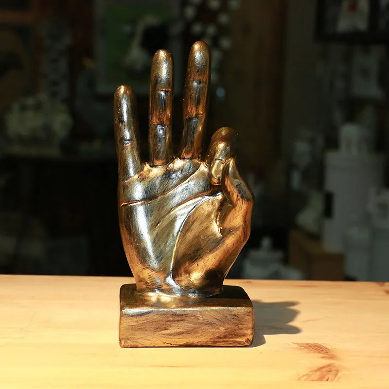 Resin hand gesture ornament in metallic finish on wooden surface