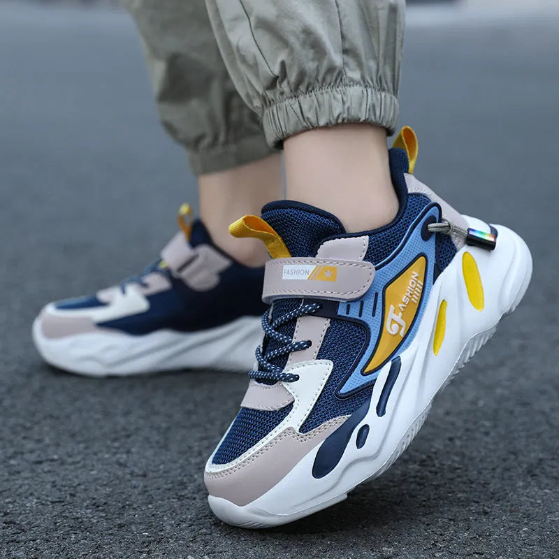 Boy's blue sports running shoe with velcro strap and mesh upper on a hard ground surface.