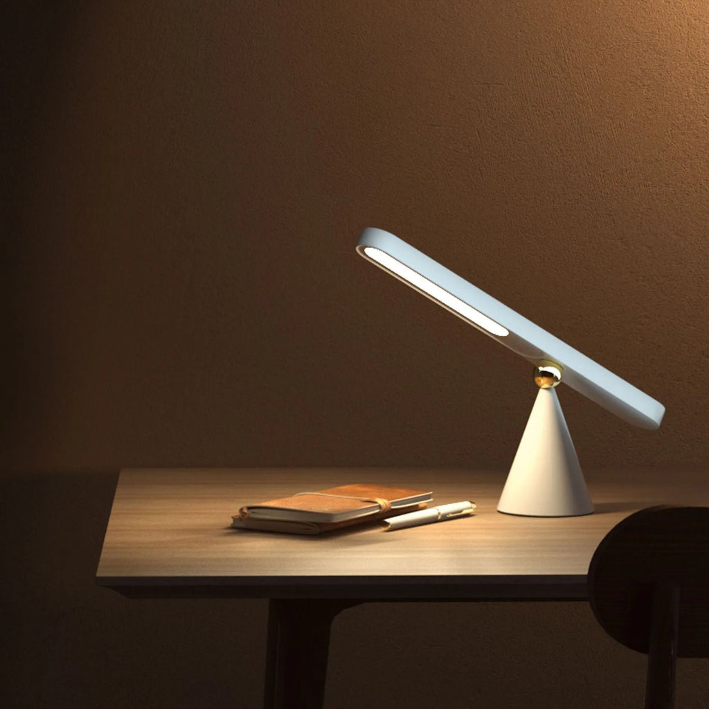 White geometric desk lamp with magnetic base mounted on a metal wall surface.