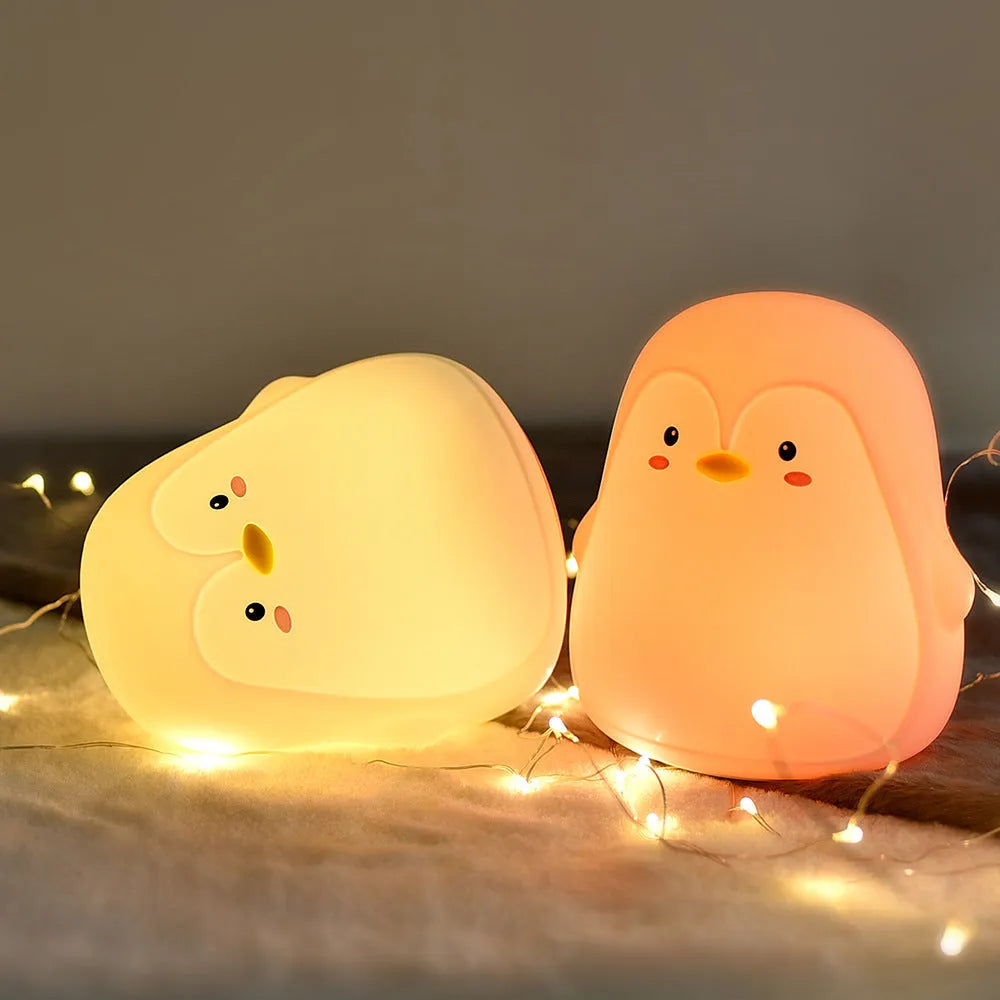 Soft white silicone penguin-shaped rechargeable night light on a surface.