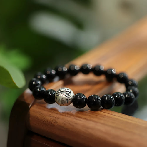 Close-up of a black agate bead bracelet with a sterling silver adjustable clasp on a wrist.