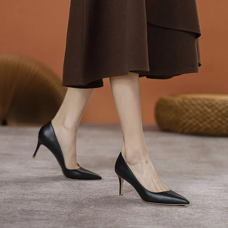 Black pointed-toe high heel pump with a stiletto heel on a plain background.