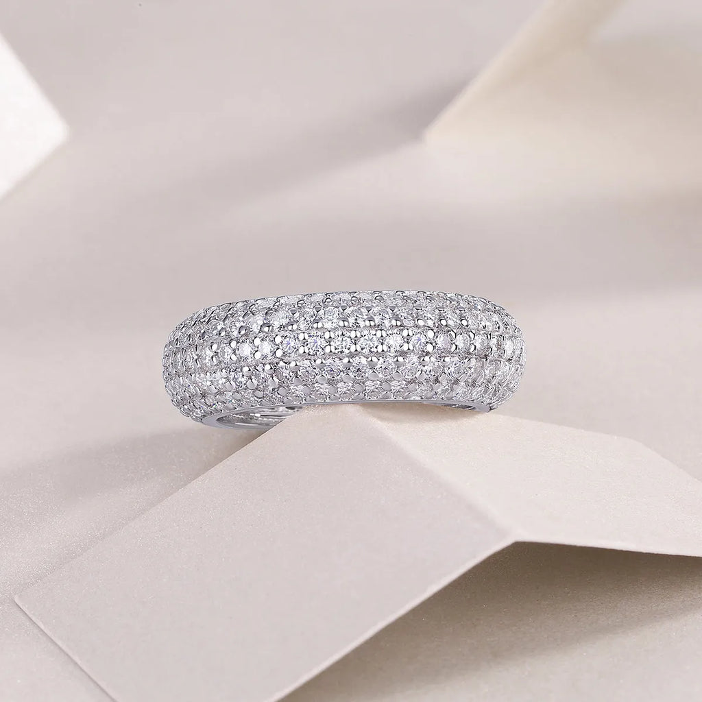 Moissanite wedding ring with S925 silver platinum plated band on flat surface showing stone and certificate
