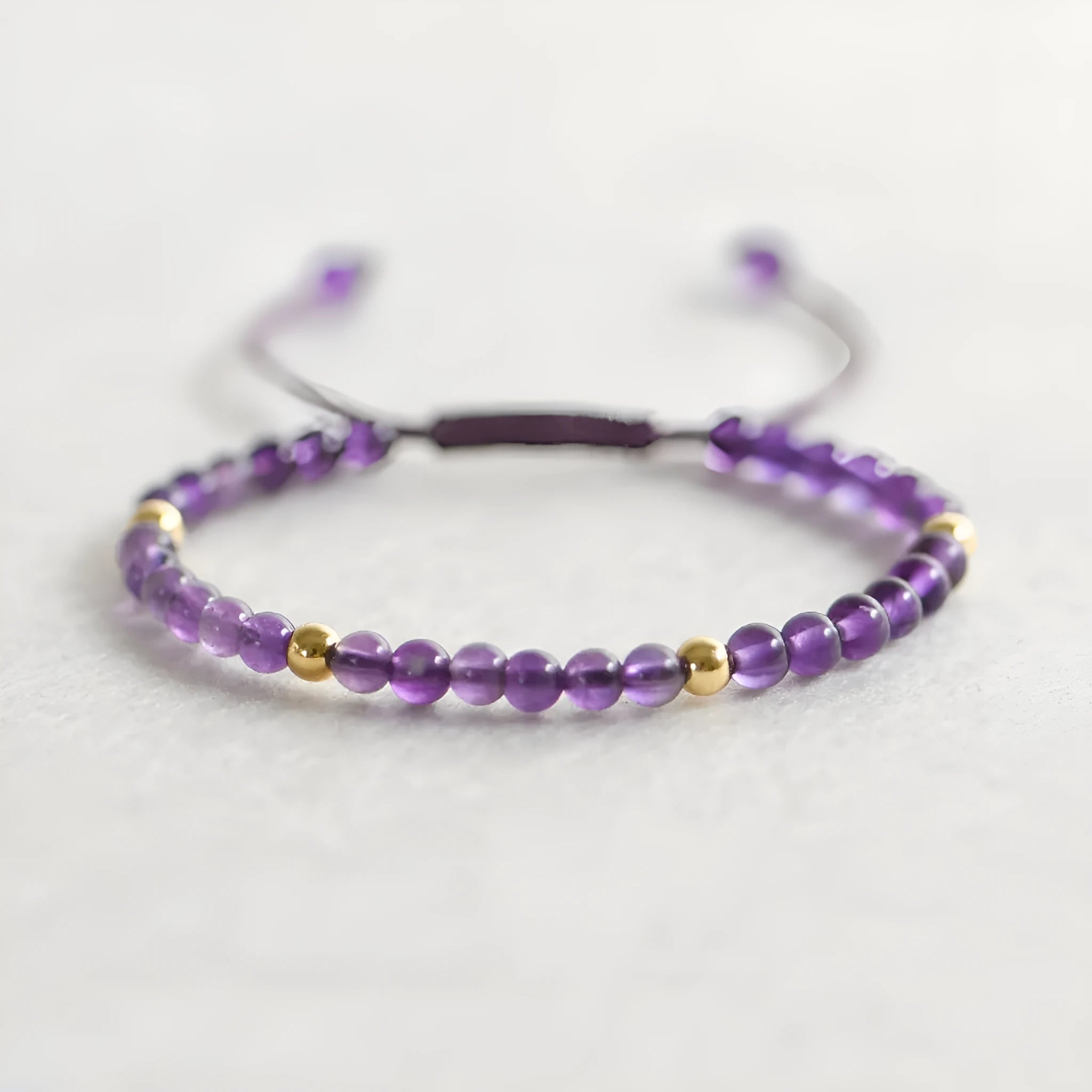 Handmade purple amethyst and 14K gold bracelet with 4mm round beads on a wrist.