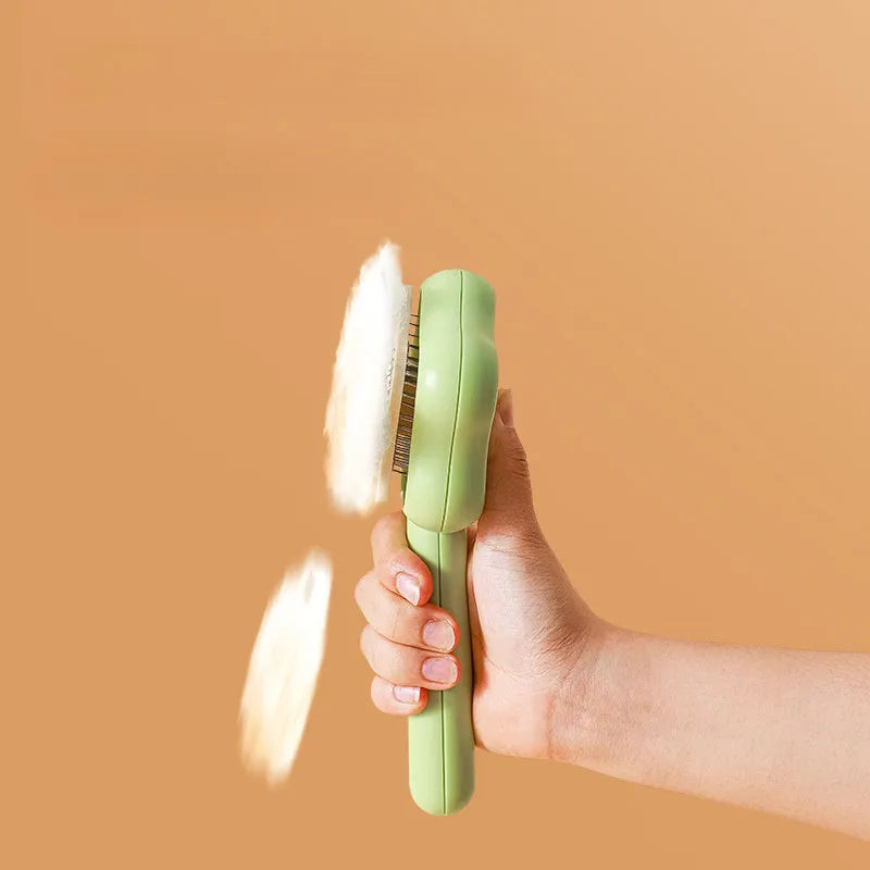 Green self-cleaning pet comb with stainless steel needles on a white background.