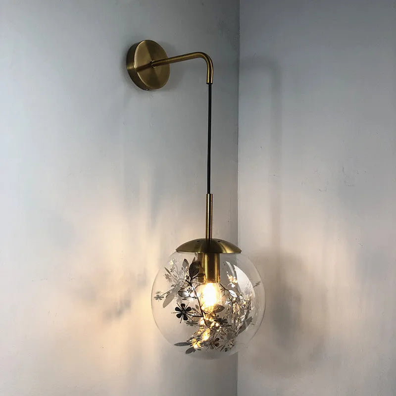 Modern golden flower glass wall lamp mounted beside a bed.