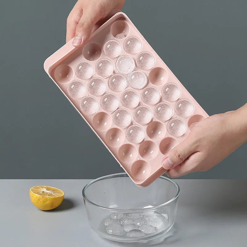 Sky blue 3D round ice ball mould tray with 18 grids next to a pink tray with 33 grids.