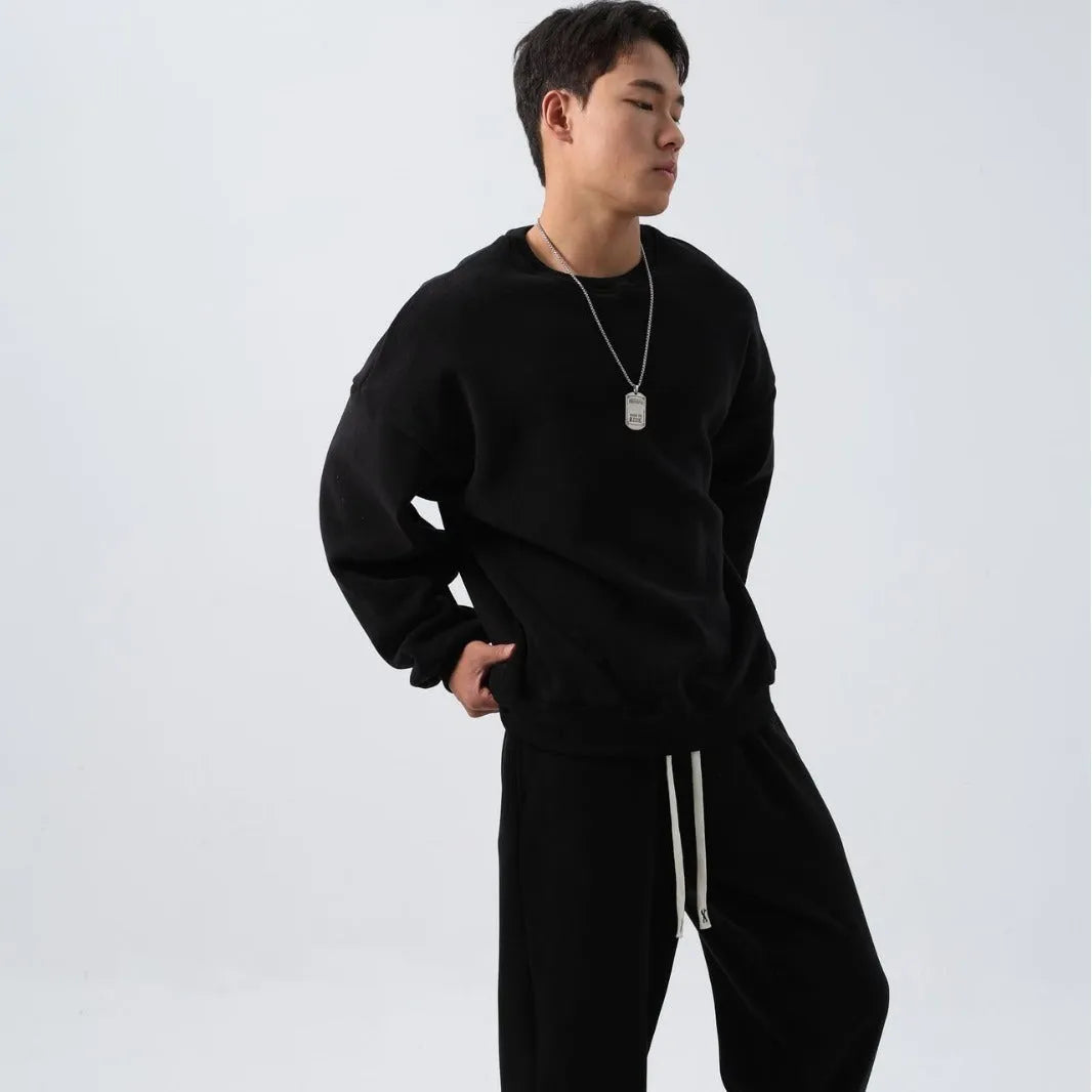 Man wearing a loose black polar fleece winter sports suit with crew neck coat and trousers