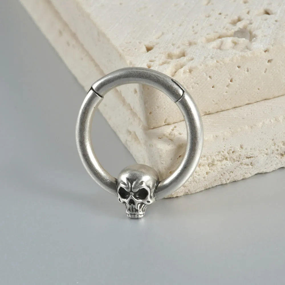 A pair of antique silver copper punk earrings featuring three small detailed ghost heads on a horizontal bar.