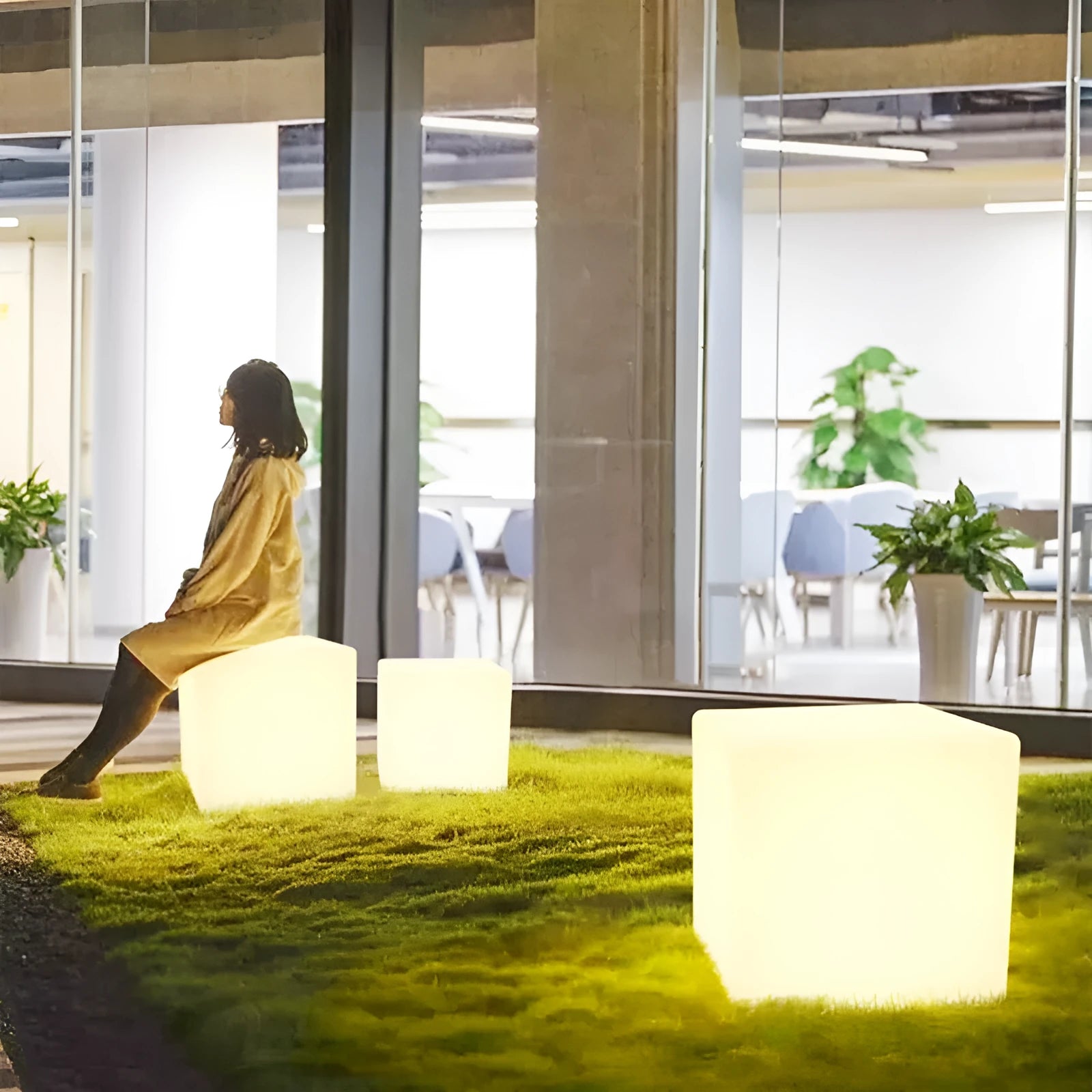 Modern square LED cube light stool in a garden setting, showcasing its clean design and luminous top.