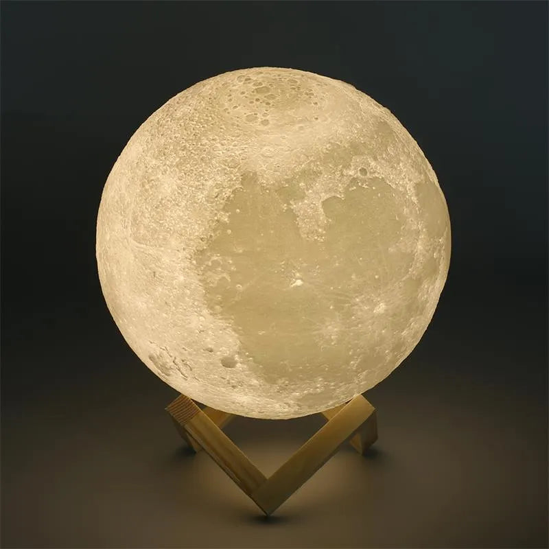 3D printed white moon lamp on a wooden holder, showing detailed lunar surface and a glowing yellow light.