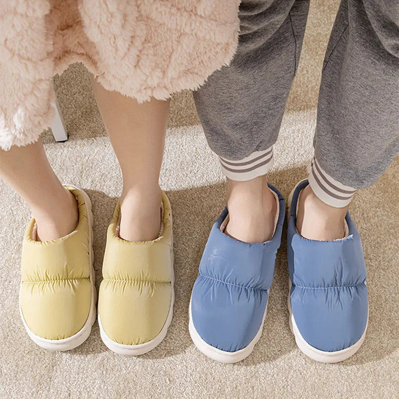 Blue down cotton winter slippers with a thick rubber sole and plush lining, shown on a wooden floor.
