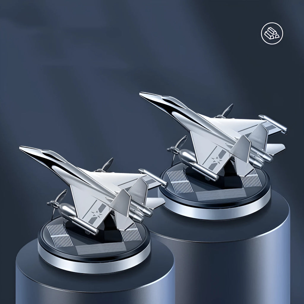 Solar-powered rotating fighter jet perfume ornament in silver, gold, blue, and red colours on a wooden surface.