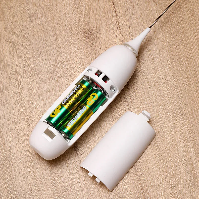 A handheld electric milk frother and blender in black and white colours on a kitchen counter.