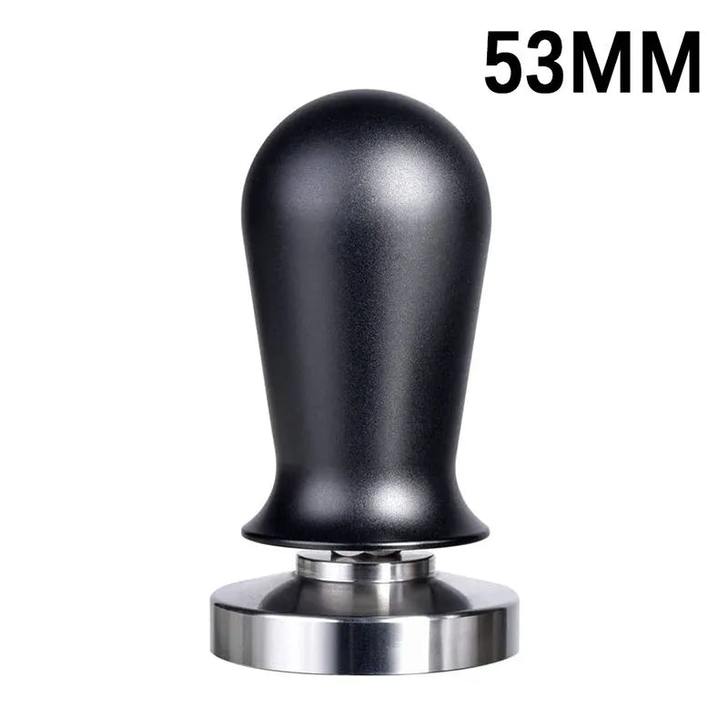 Black and red coffee tamper powder press tool with stainless steel base on a wooden table.