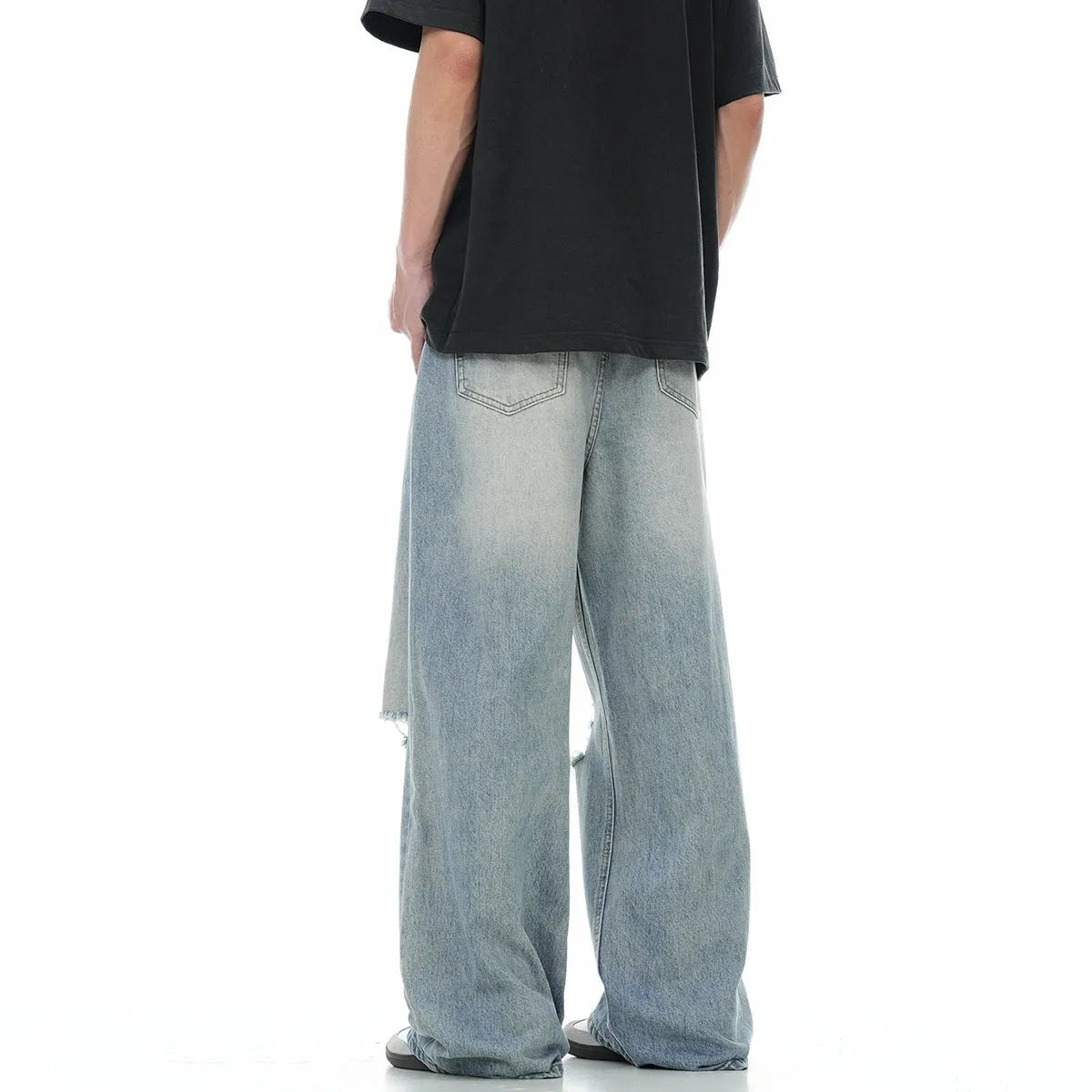 Man wearing blue ripped straight-leg jeans in a retro style with a zip fly.