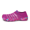 Women's camouflage pattern water shoes with Flyknit upper and flat rubber sole on a rocky shore.