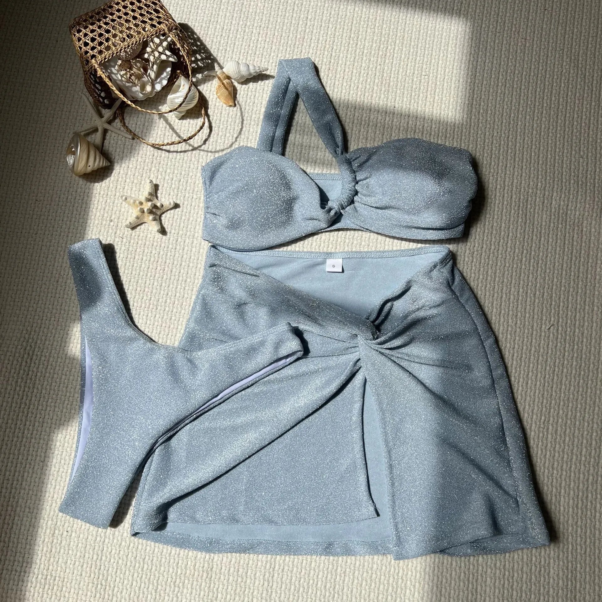 Light green one-shoulder glossy swimsuit three-piece set with matching skirt and pants.
