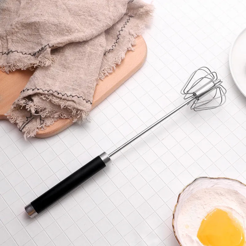 Self spinning whisk with stainless steel head and black handle on a white background