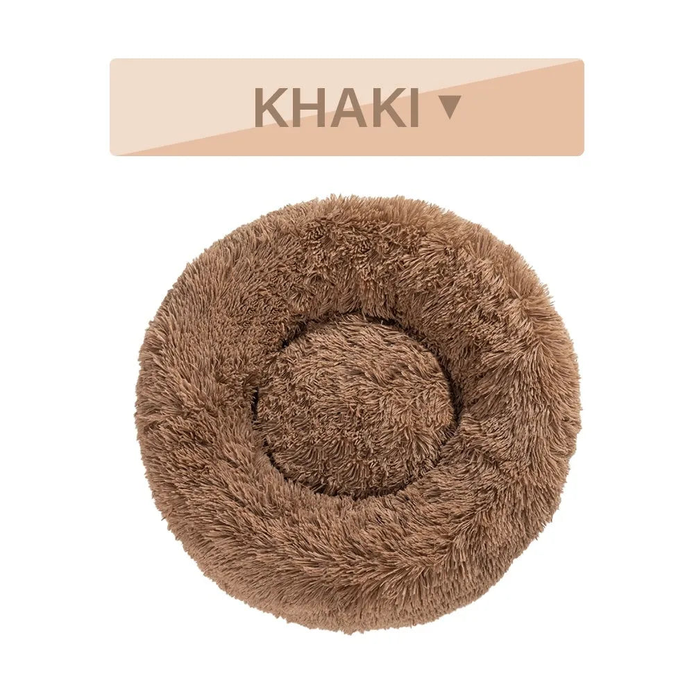 Fluffy grey donut-shaped dog bed with high plush sides on a wooden floor.