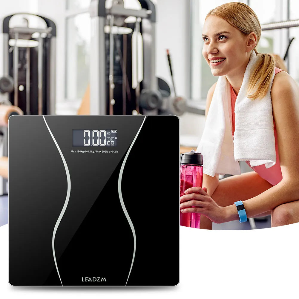 Black electronic digital body scale on a floor, showing a weight readout.