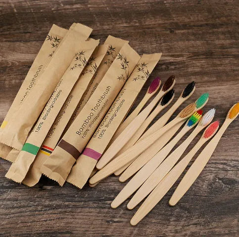 Set of ten bamboo toothbrushes with charcoal bristles in assorted colours on a plain background