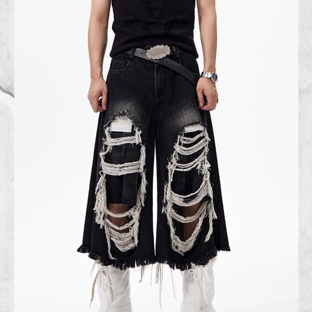 Black wide-leg cropped jeans with a ripped patch detail on the leg, shown on a model.