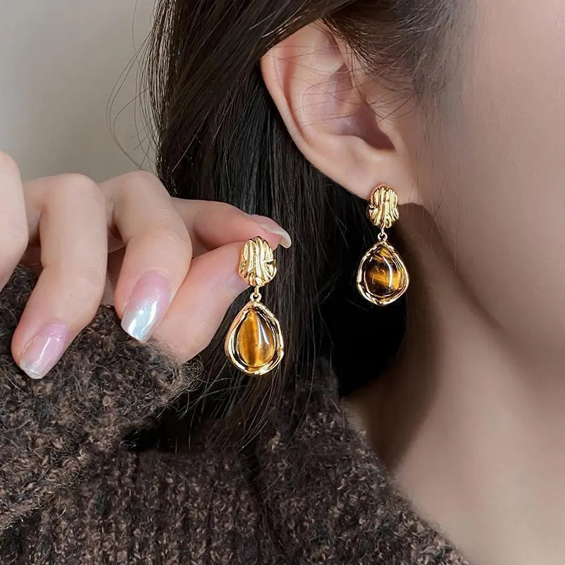 Set of three pairs of geometric holiday earrings: round studs, irregular amber studs, and tassel drop earrings.